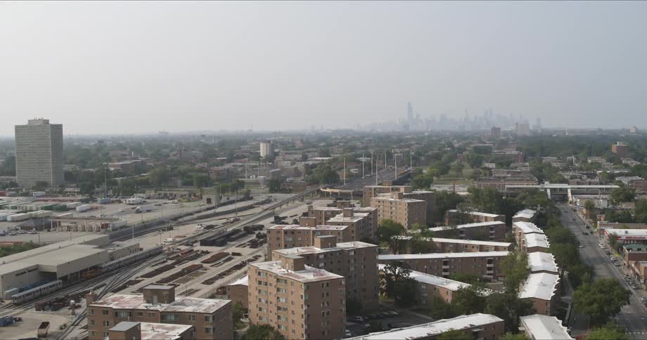 Buildings and trees in a city sit under the misty sky