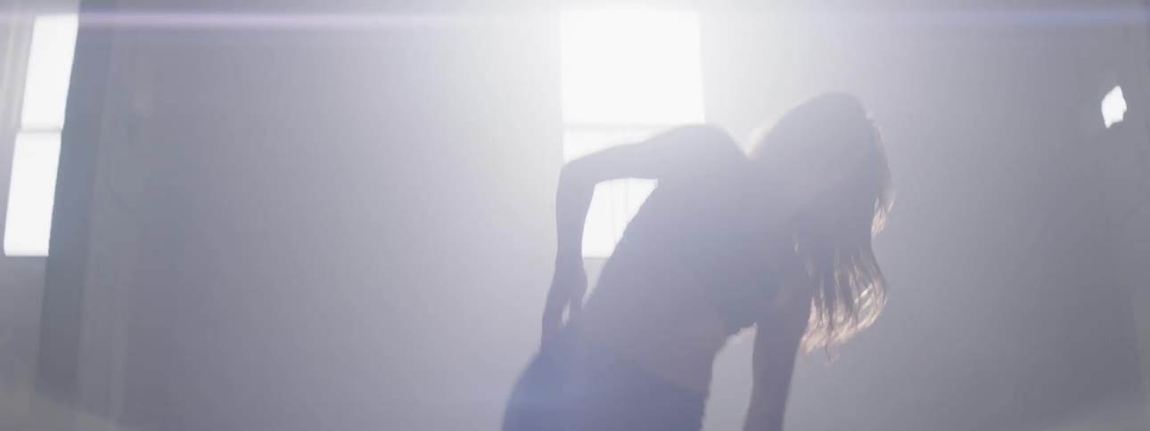 Girl dances in the light of sun shining from the window during daytime
