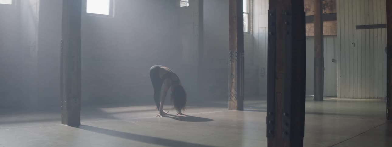 A dancer stretches in a dark room