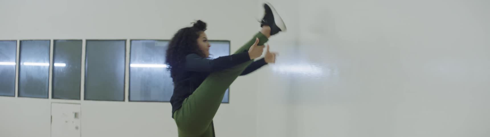 Dancer stretches against wall in dance studio