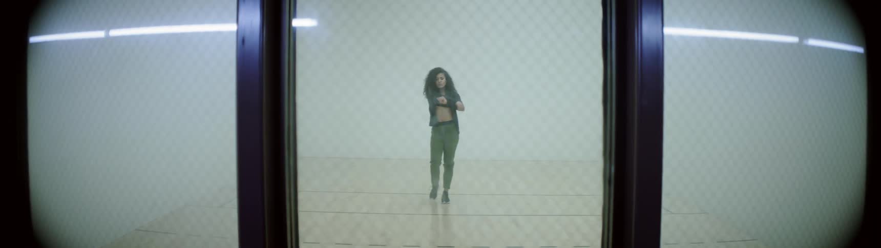 Girl warms up before beginning to dance between four white walls