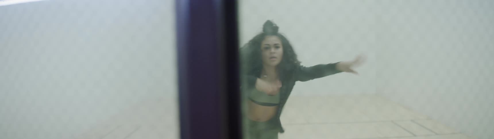 Curly haired girl dances in between four white walls