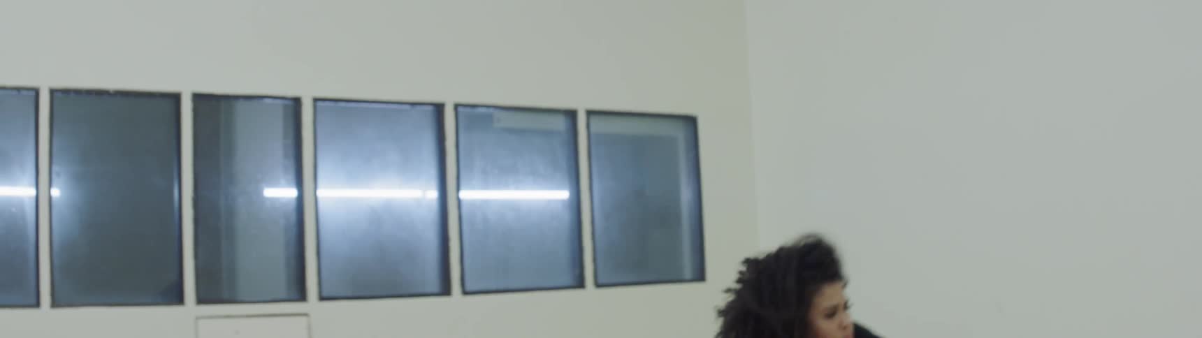 A woman hip hop dancing in front of a row of windows