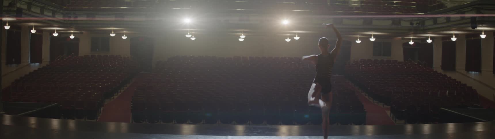 A woman dances before an empty theater