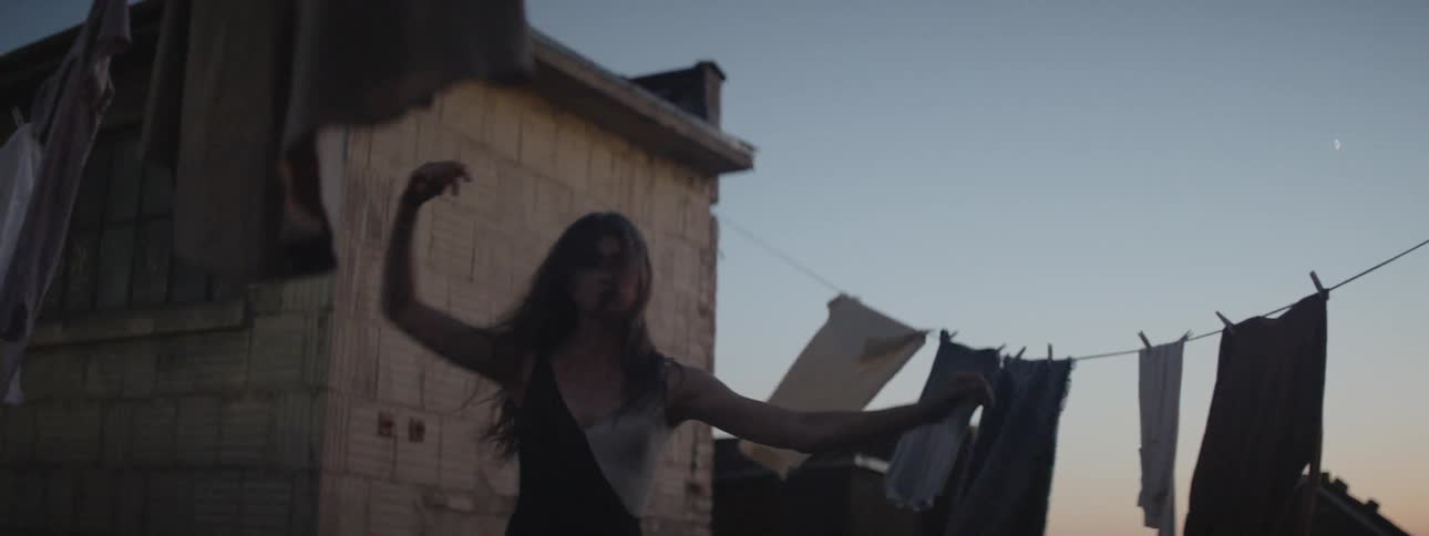 A woman is dancing on the roof at sunset