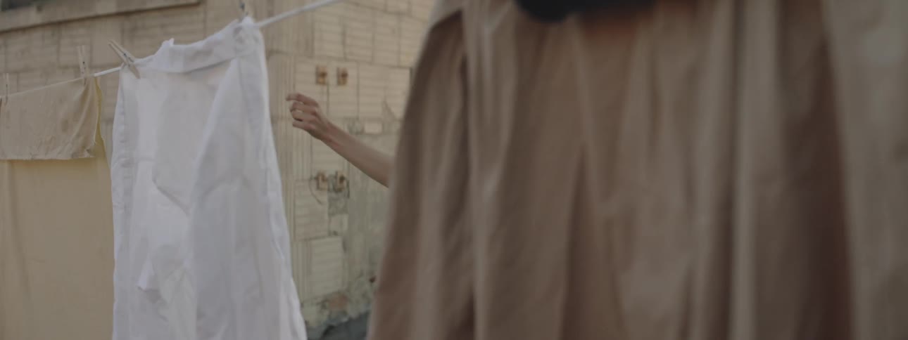 Woman dances between clothes that are hanged to dry