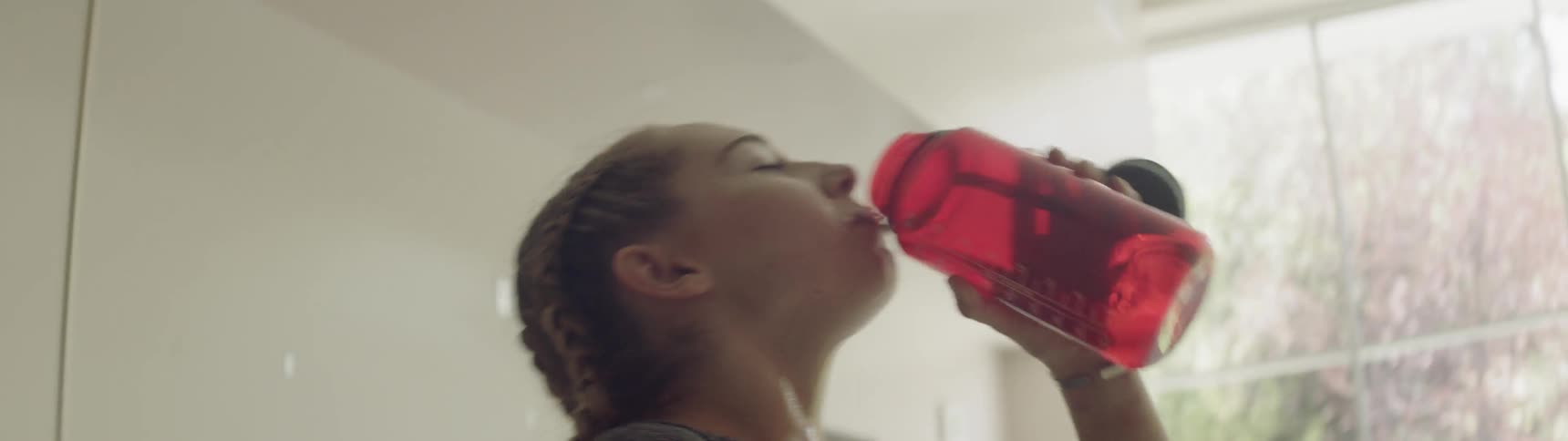 A woman fills up a water bottle and drinks it