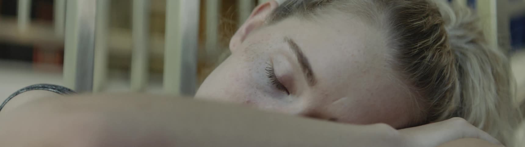 A young woman wipes her eyes and lays her head on her arm