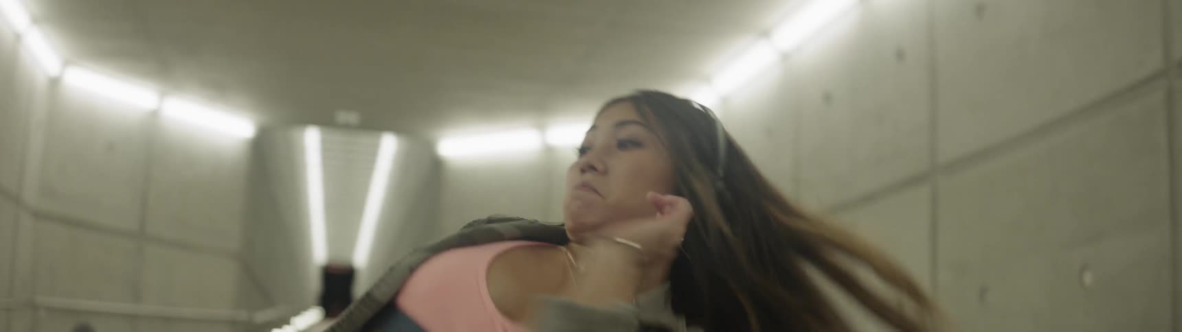 Asian girl wearing headphones dances in the underground hall