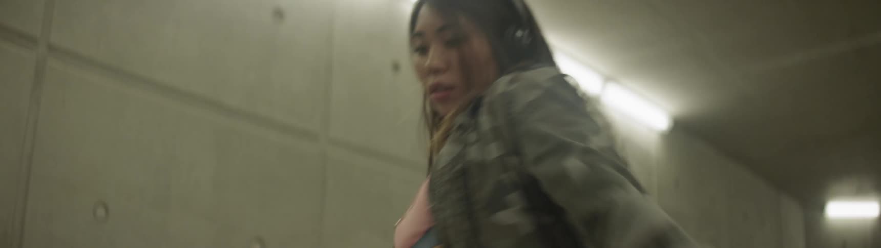 A woman dances in a well lit tunnel wearing headphones