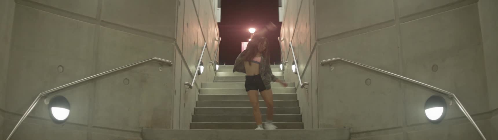 Girl dances on underground stairs at night