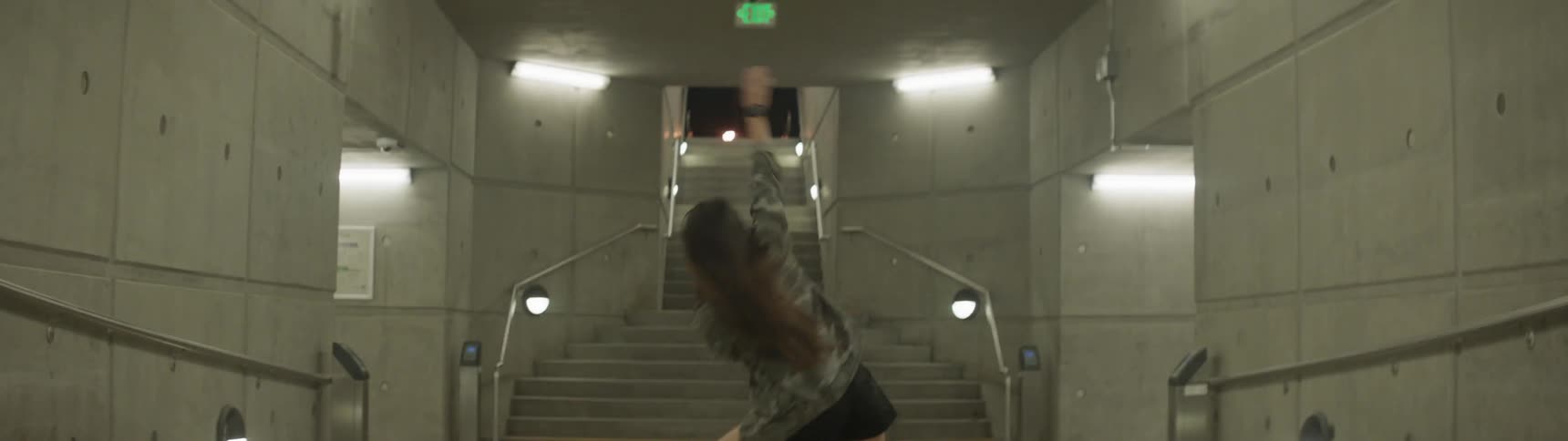 A woman dancing in a tunnel in front of a stone staircase