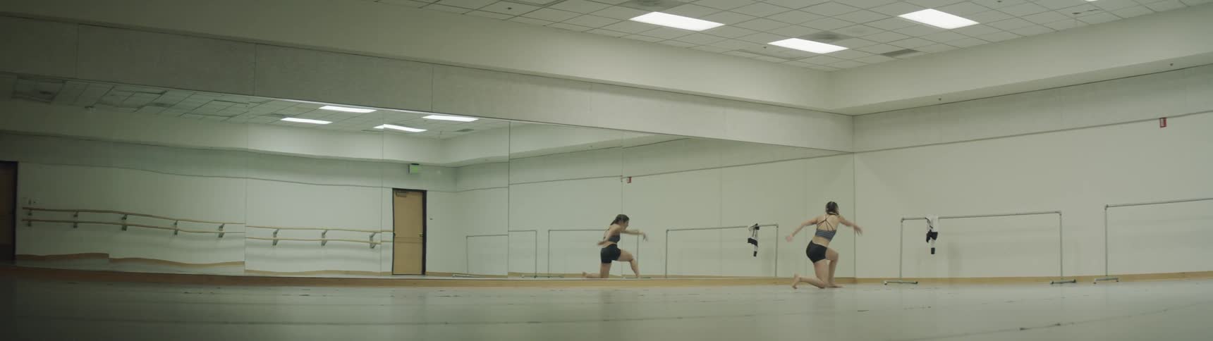 A woman in a dance studio practicing her dancing in front of a mirror