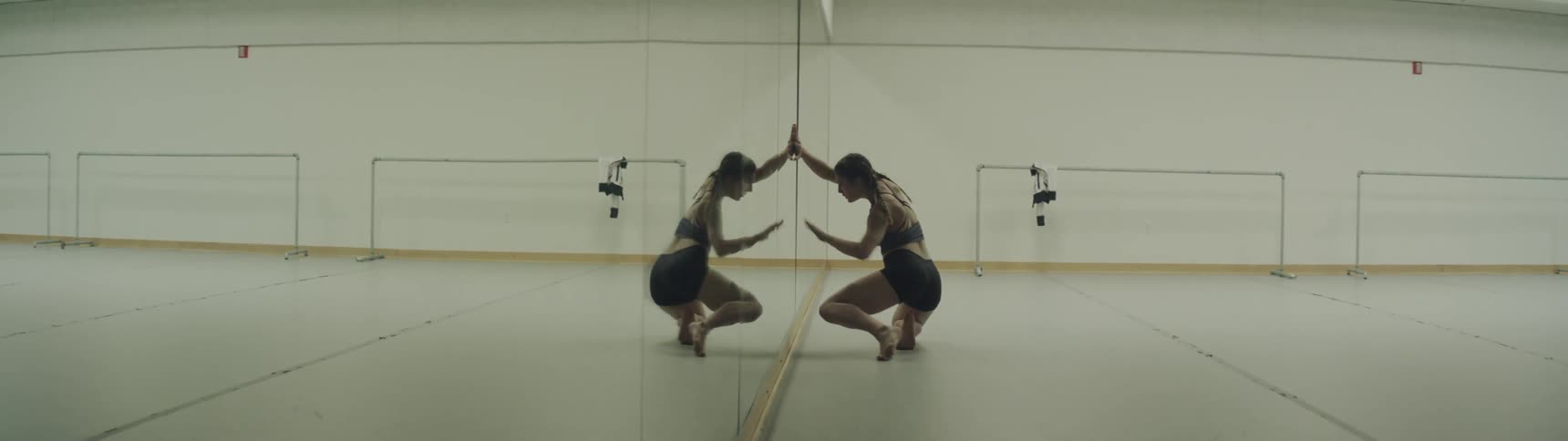 Girl dances in front of mirror in a big gym