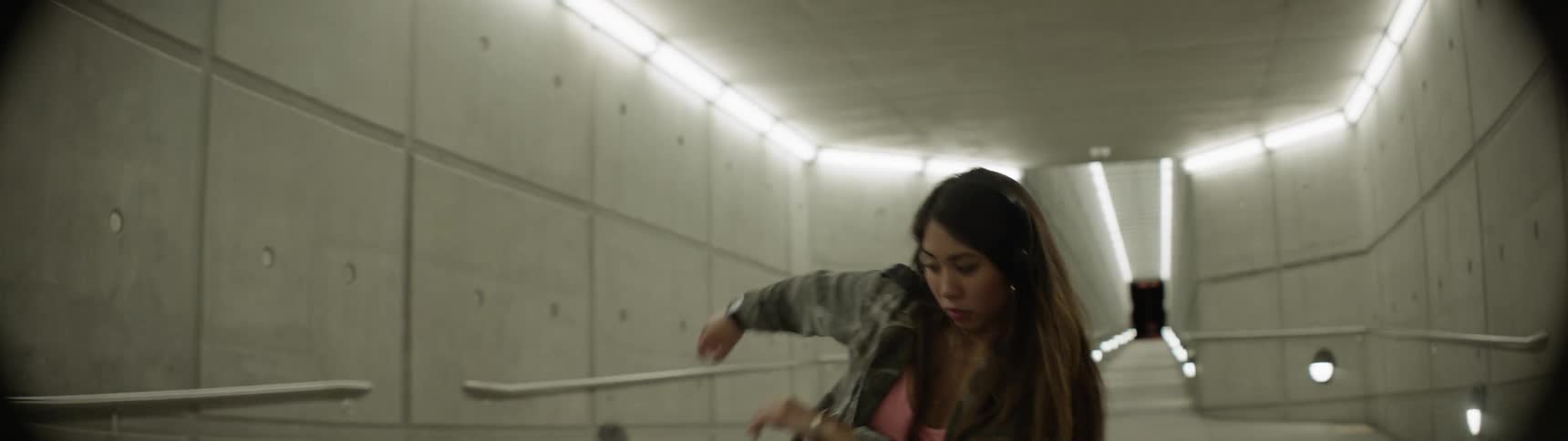 An asian teen dances in an empty hallway