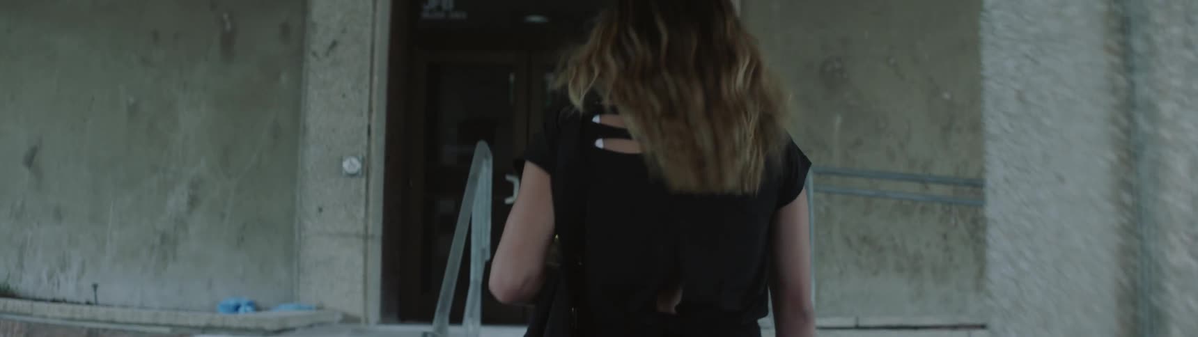 Girl climbing up the stairs enters the building door during daylight