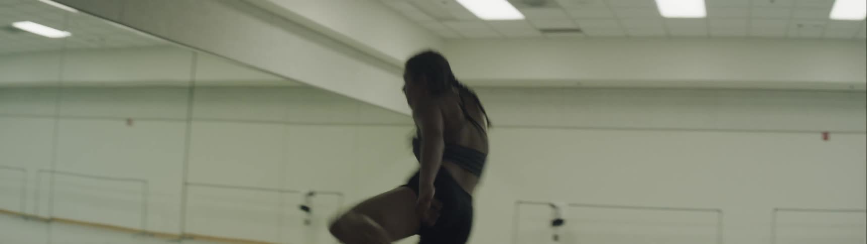A woman in a dance studio dancing in front of a mirror