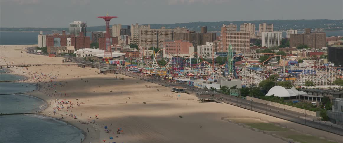 A cityscape with a beach full of people on the shore