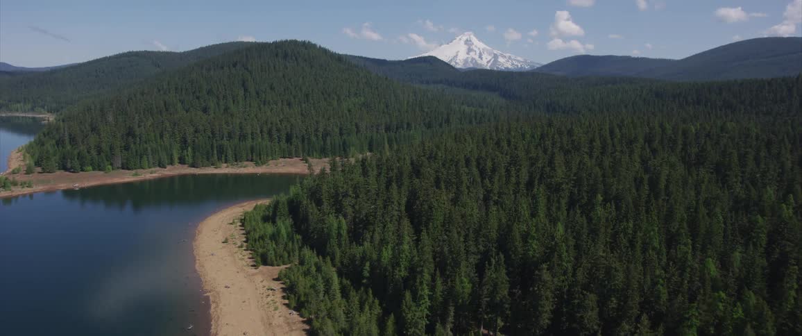 The camera flies over a lake with a mountain in the distance