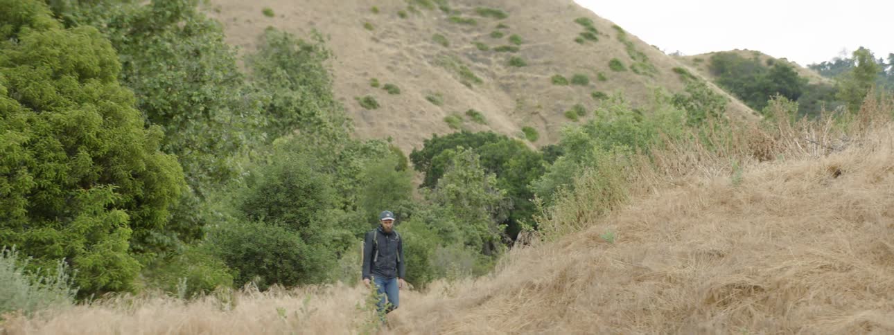 A man walks on a hillside path