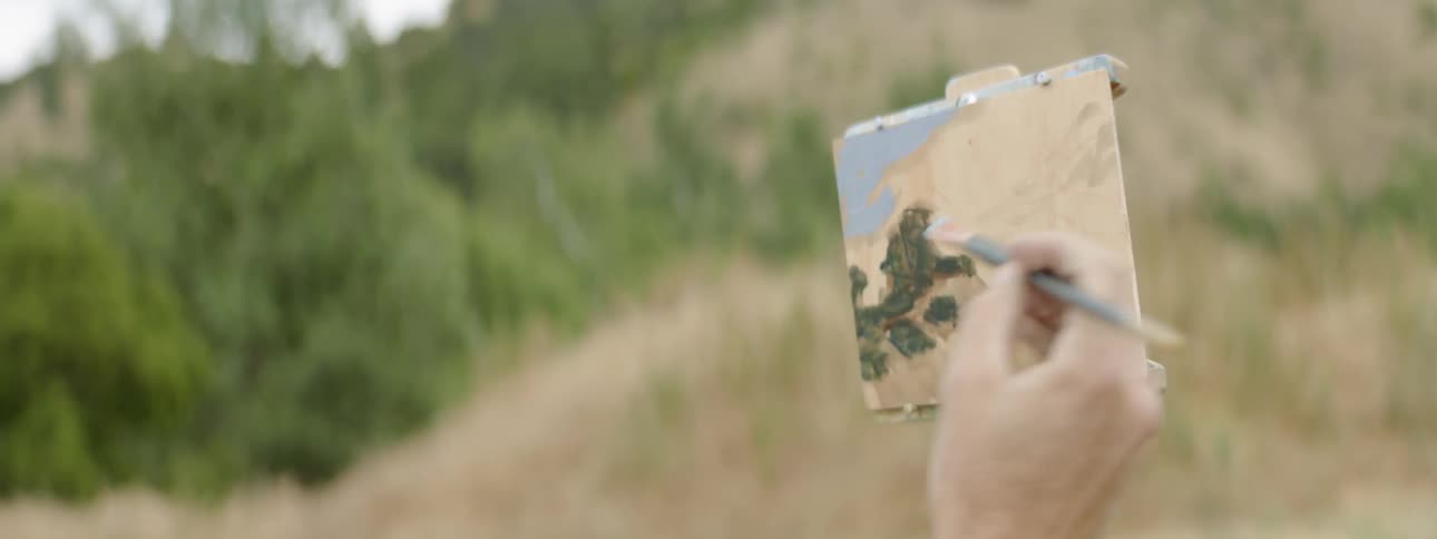 A man painting on a small piece of paper