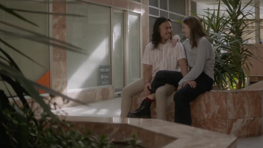 A young couple are intertwined on a marble bench