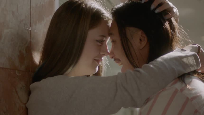 A young woman strokes her boyfriends hair as they joke together
