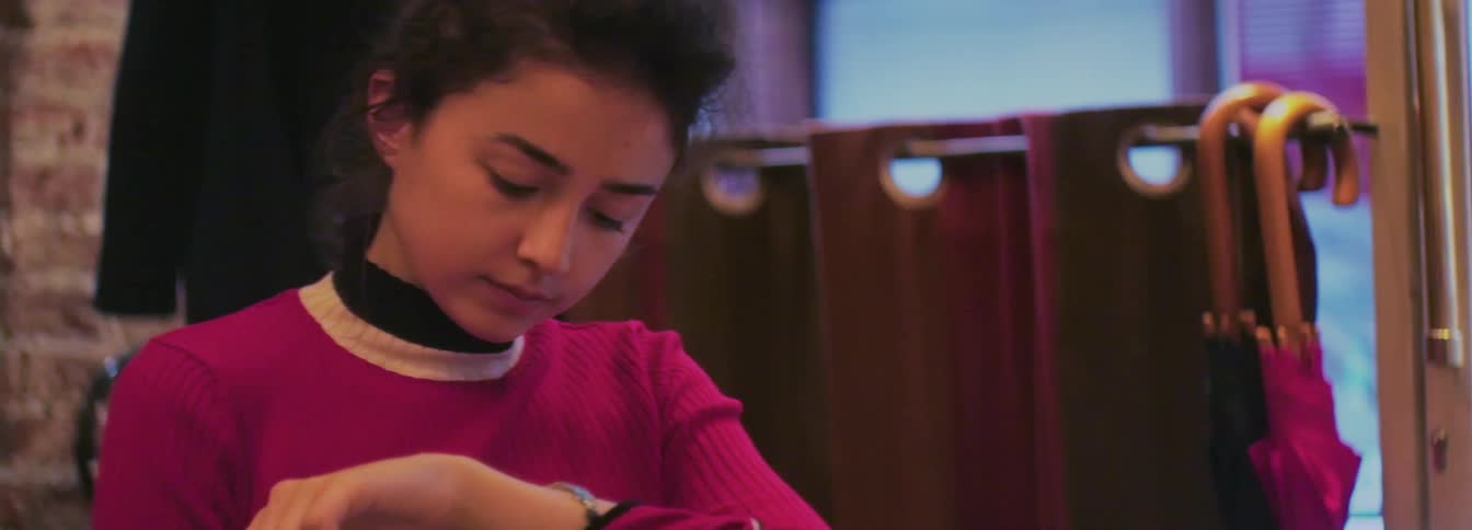 A woman checks her wrist watch in a cafe