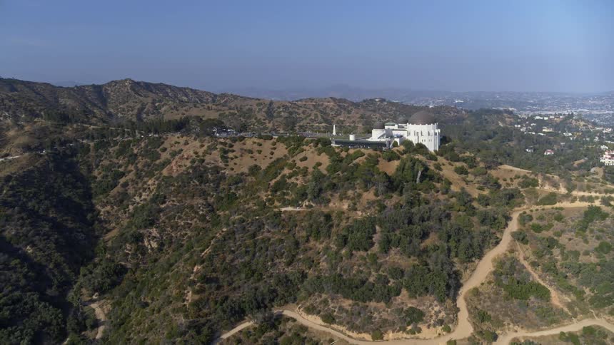 Aerial view of a large temple on top of a big hill near mountains