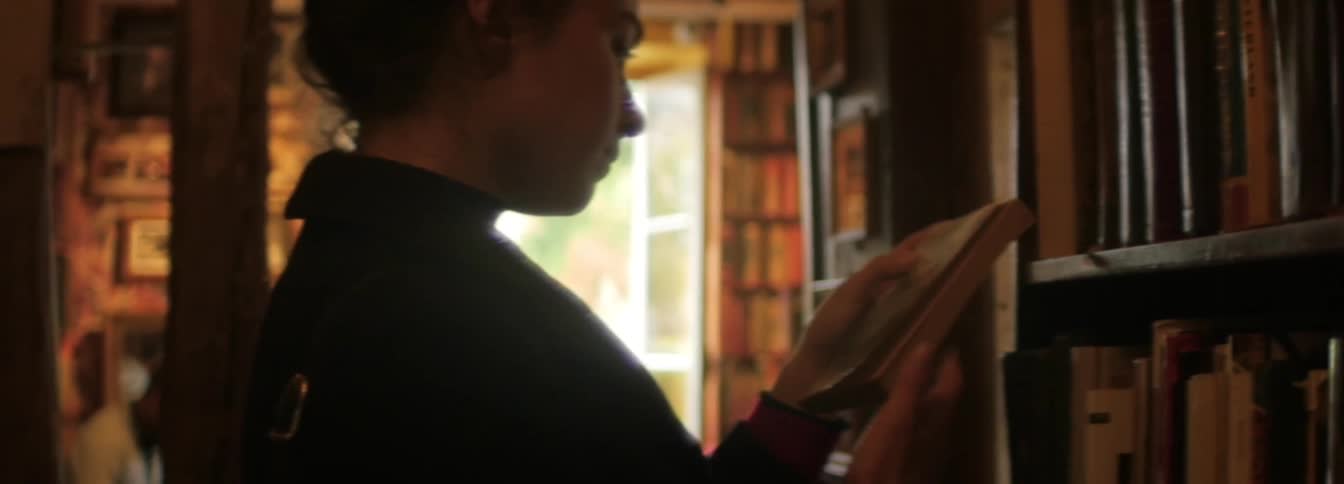 A young woman pulls a book from the library shelf