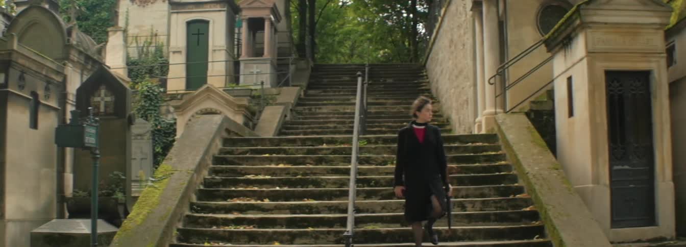 A woman walks down a set of stairs at a cemetery