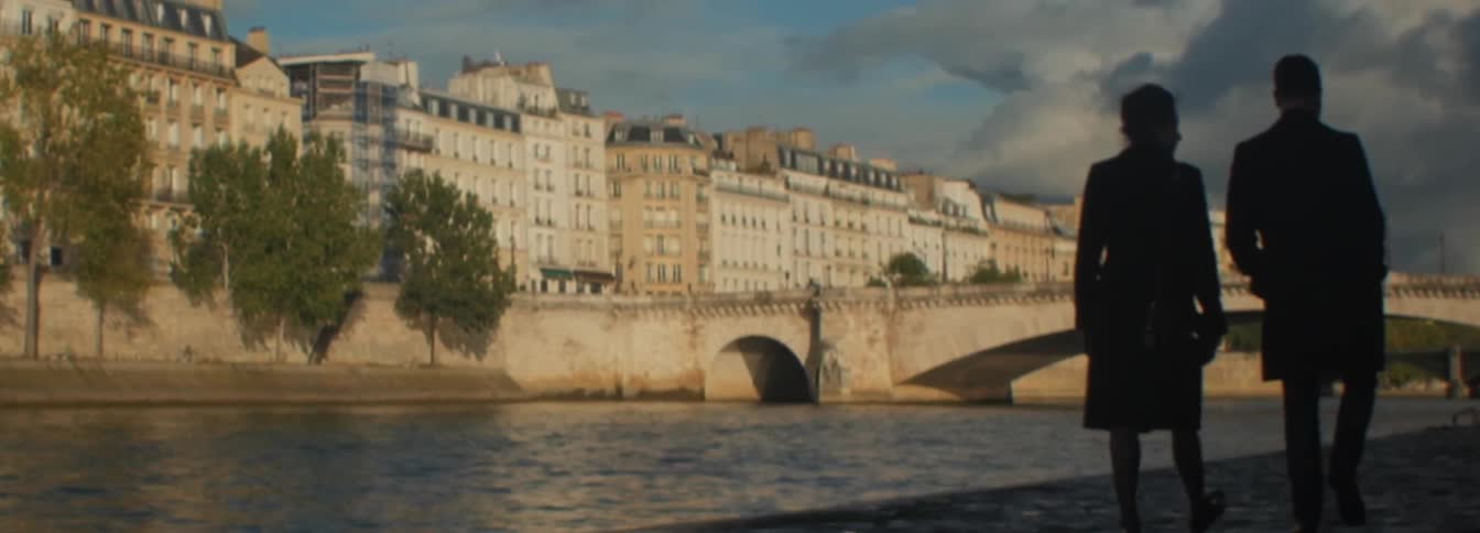 Two people walking down a path by a river