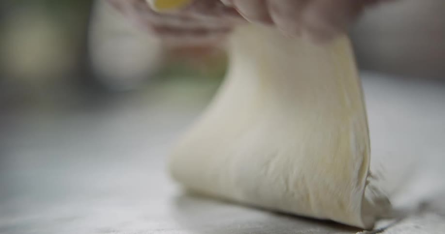 Man puts flour on the dough and spreads it indoors during daylight
