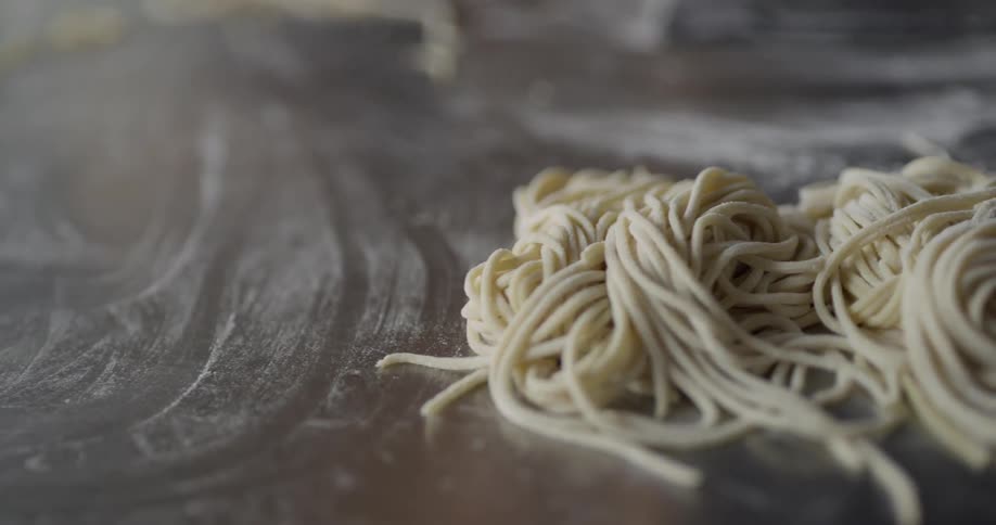 Hand picking up homemade noodles from the counter