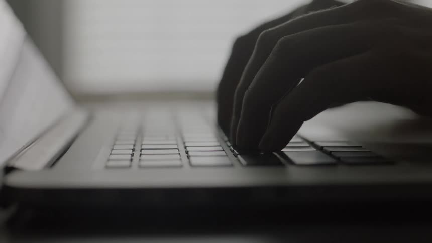 Hands typing on a laptop
