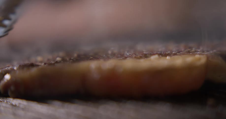 A steak is flipped and basted on a grill