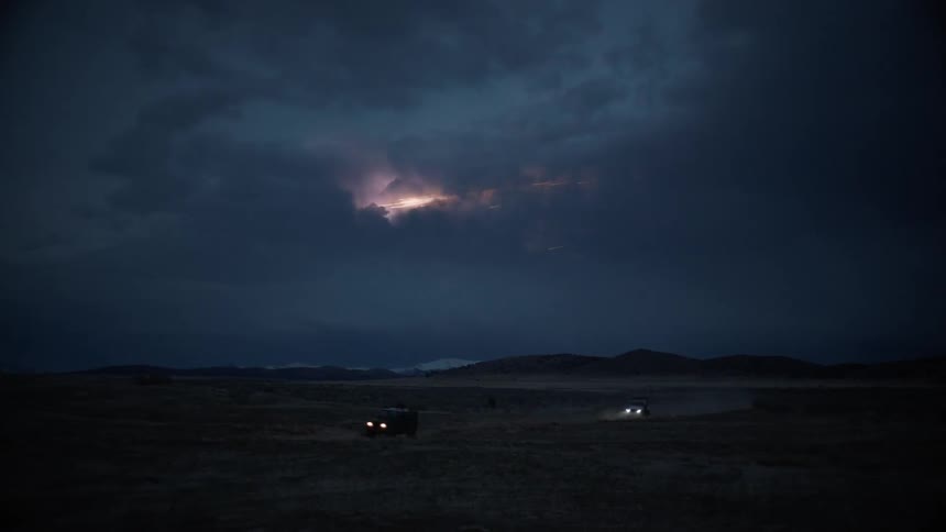 A nighttime shot of flares in the sky with cars driving