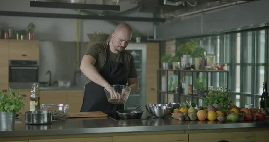A chef pours oil and ingredients into a pan