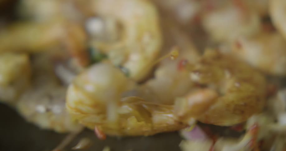 A pan of shrimp and ingredients gets tossed and sauteed