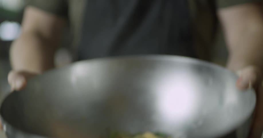 A chef tosses food in a bowl
