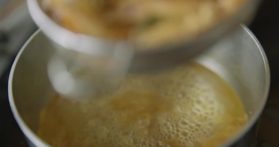 Shrimp is removed from a pot into a strainer and pushed down
