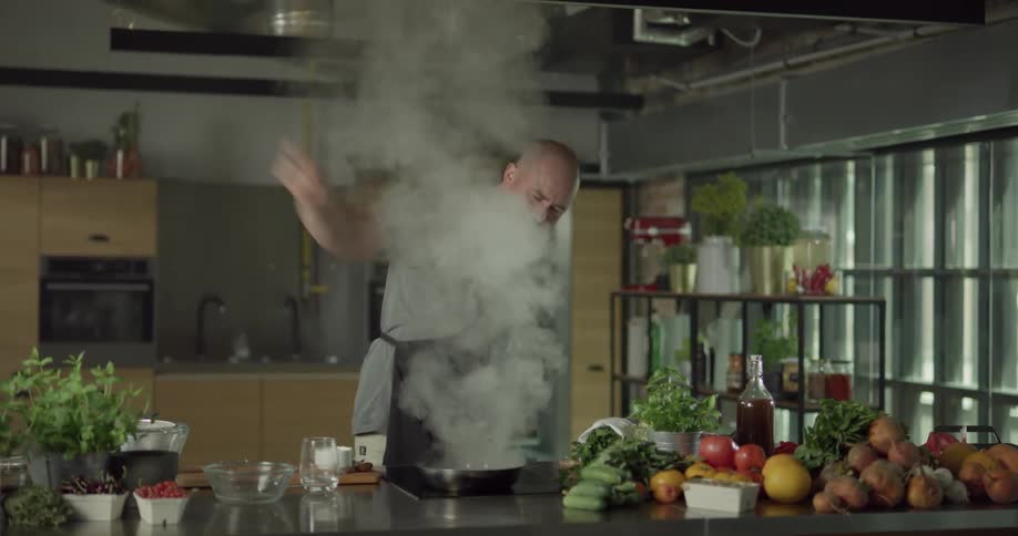 A man flipping and flambing food in a skillet