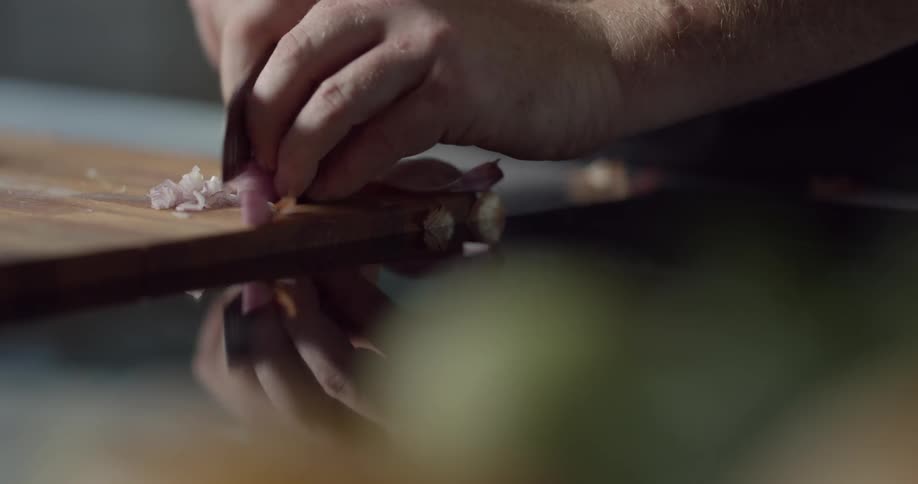 A chef chopping shallots on a cutting board