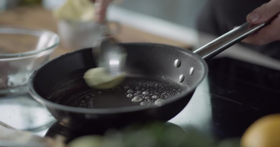 A chef scoops butter and places it in a pan