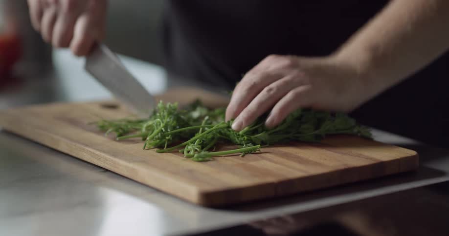 Man chops parsley on chopping board