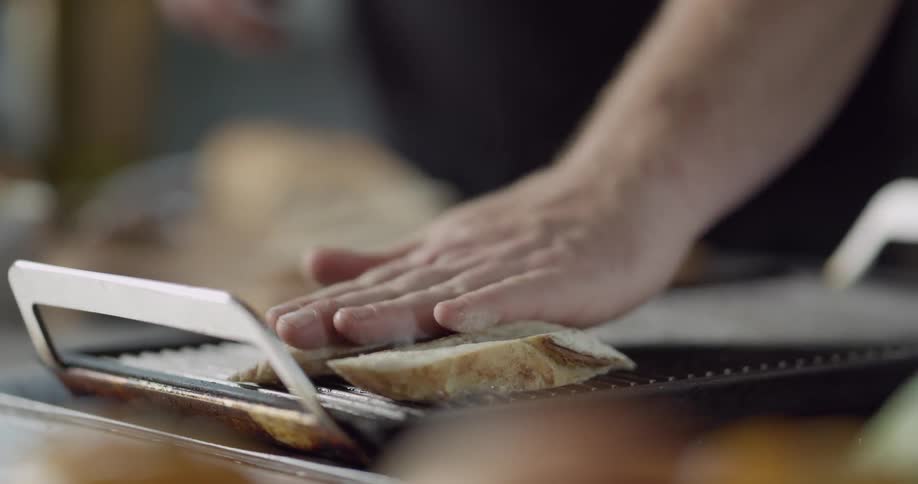 A chef laying buttered slices of bread onto a hot grill pan