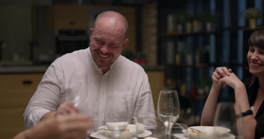 People laugh while sitting at a dinner table