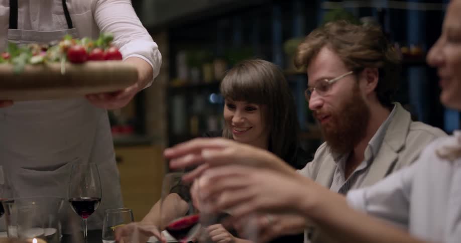 A chef serves a salad to a table of people