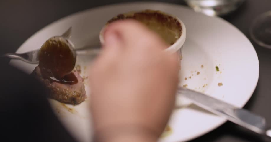 A person spoons sauce onto a plate