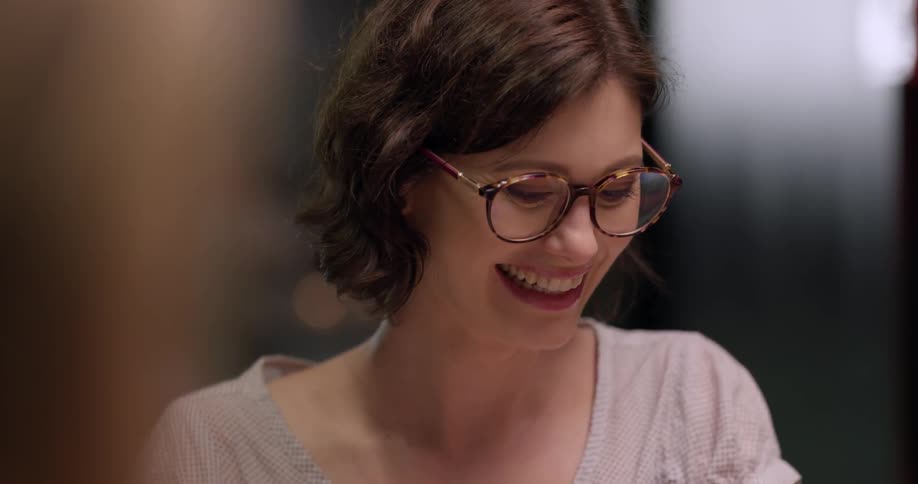Woman wearing glasses laughs and man next to her lifts up some tomatoes